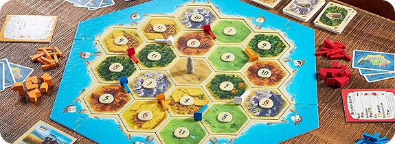 Catan társasjáték hatszögletű lapokkal, nyersanyagkártyákkal és játékfigurákkal